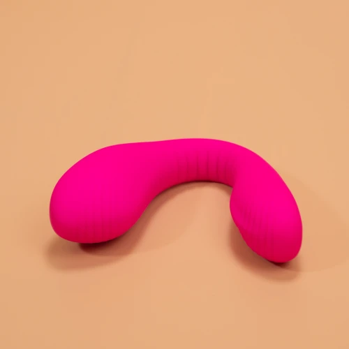 На фото изображен розовый двойной вибратор с функцией "Смарт" Lovense Dolce (Quake) для женщин на бежевом фоне.