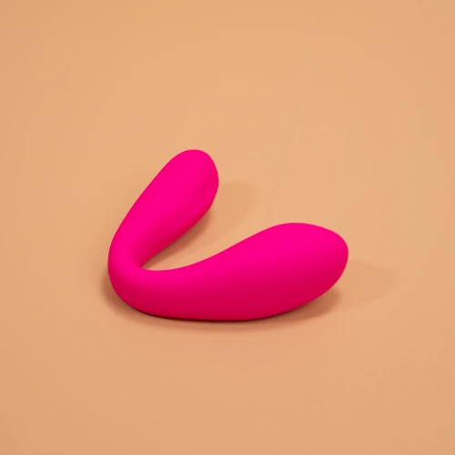 На фото изображен розовый двойной вибратор с функцией "Смарт" Lovense Dolce (Quake) для женщин на бежевом фоне.