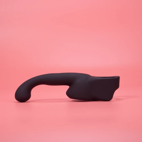 На фото изображена черная насадка Lovense Domi Male Attachment для вибраторов Domi и Domi 2 для мужчин на розовом фоне.