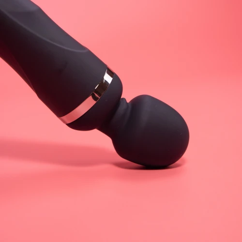 На данном изображении показан черный вибромассажер на розовом фоне.