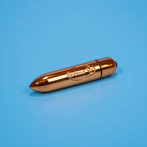 На фото зображено золотисту віброкулю з суперточною стимуляцією клітора та повним водозахистом Rocks Off 1-Speed ​​Copper для жінок на блакитному тлі.