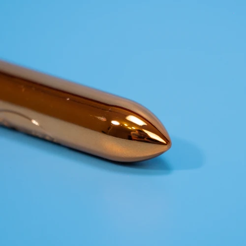 На фото зображено золотисту віброкулю з суперточною стимуляцією клітора та повним водозахистом Rocks Off 1-Speed ​​Copper для жінок на блакитному тлі.