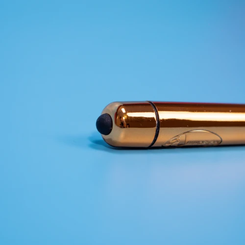 На фото зображено золотисту віброкулю з суперточною стимуляцією клітора та повним водозахистом Rocks Off 1-Speed ​​Copper для жінок на блакитному тлі.