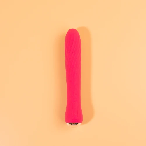 На фото изображен розовый вибратор, лежащий на бежевом фоне.