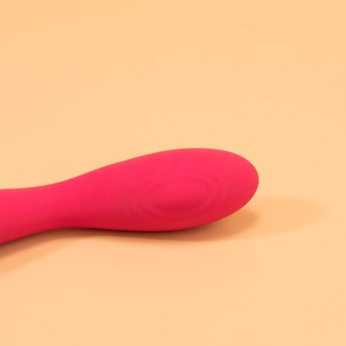 на фото зображений близько розташований рожевий вібратор який лежить горизонтально та має срібні вставки 