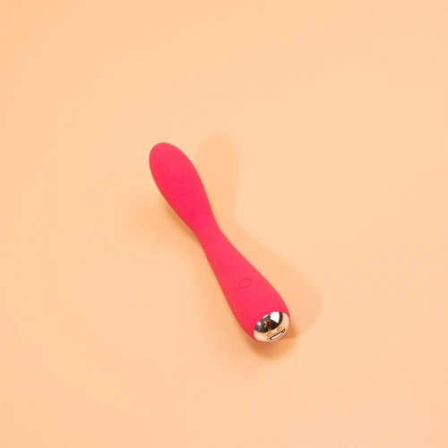 на фото зображений близько розташований рожевий вібратор який лежить горизонтально та має срібні вставки 