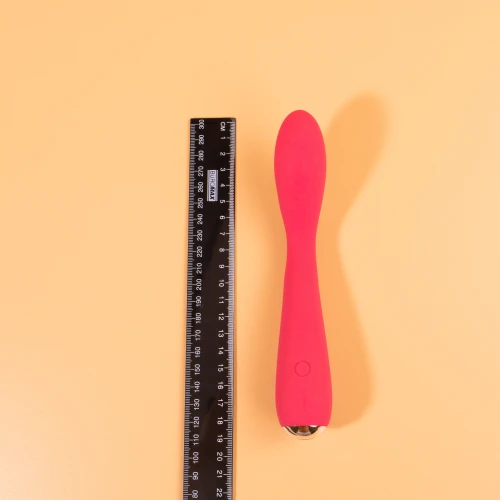 На фото зображено рожевий вібратор, поруч із яким розташована чорна лінійка для демонстрації його розміру.