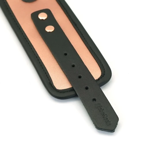 На фото зображені чорні наручники з золотим рожевим Liebe Seele Rose Gold Memory Wrist Cuff на білому тлі