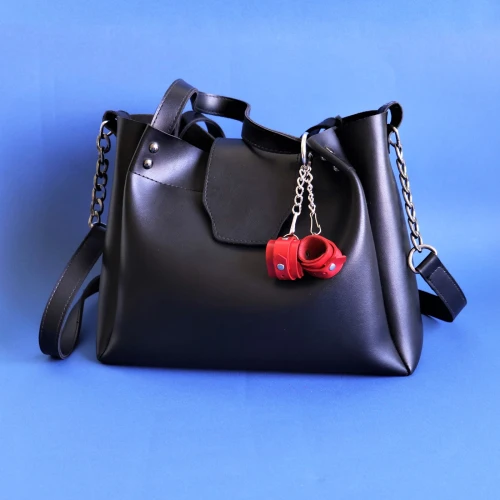 На фото зображено червоний брелок наручники для ключів унісекс на світлому фоні.