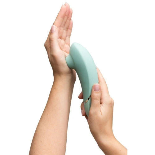 На фото изображен зеленый вакуумный стимулятор Womanizer Next Sage для женщин на белом фоне.