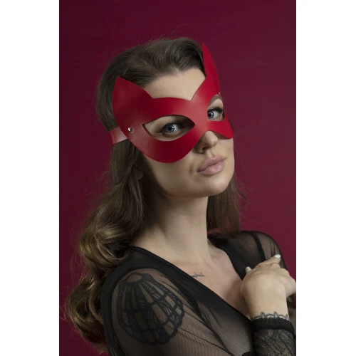 На фото изображена красная БДСМ маска на глаза Feral Feelings — Kitten Mask для женщин на бордовом фоне
