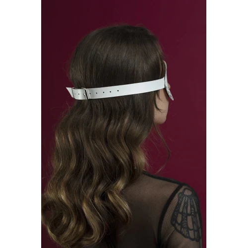 На фото изображена белая маска на глаза с заклепками Feral Feelings — Blindfold Mask для женщин на бордовом фоне