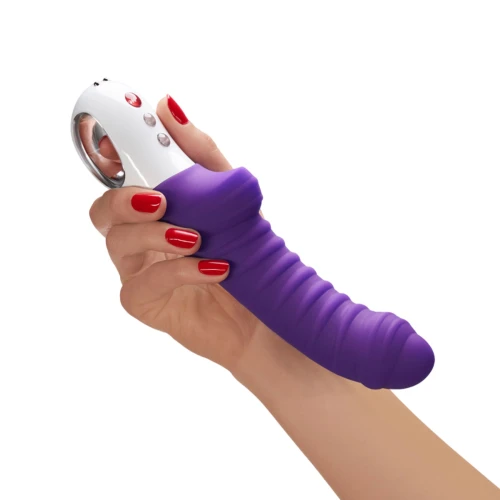 На фото фіолетовий вібратор із білою основною частиною, який тримають у руці.
