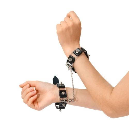 На фото зображено чорний бондажний набір: нашийник з повідцем, наручники та поножі Art of Sex - Cassandra унісекс на світлому тлі