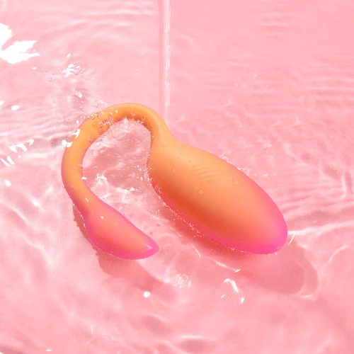 На фото изображено оранжевое смарт виброяйцо Magic Motion Flamingo Max Orange для женщин на разноцветном фоне.