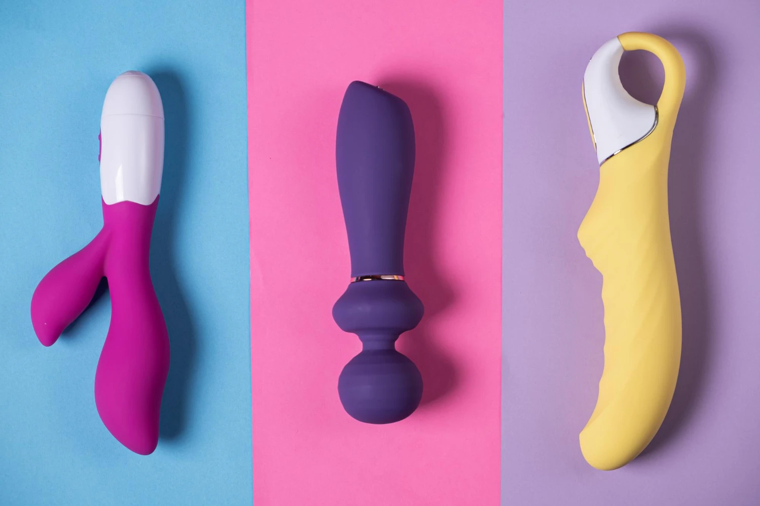 на фото зображені три кольорових великих вібратора для жінок на різнокольоровому фоні