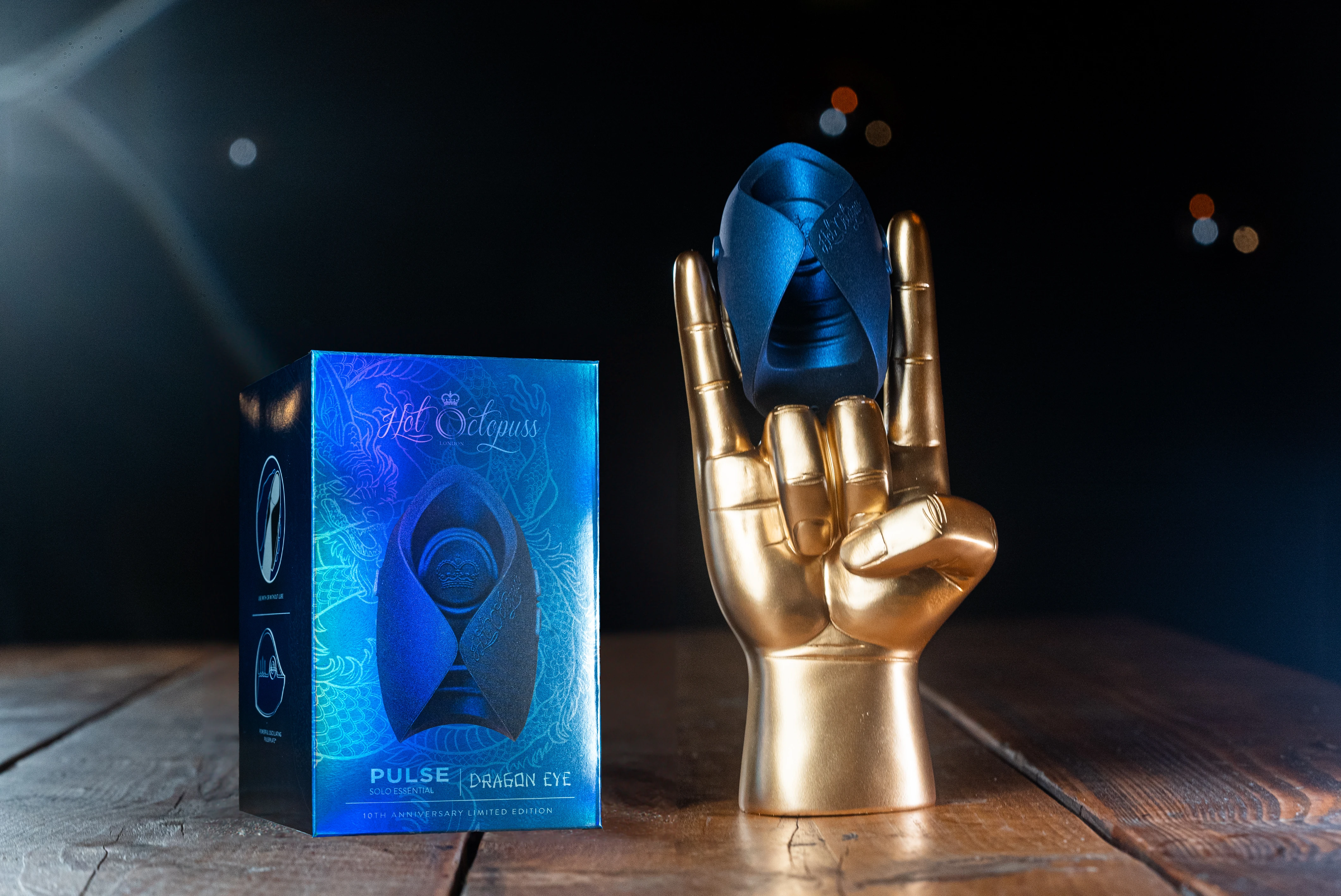 на фото изображен синий мастурбатор Hot Octopuss на пластмассовой золотой руке на черном фоне