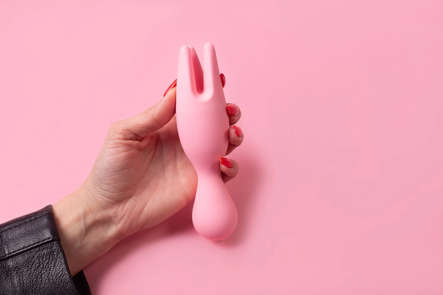 на розовом фоне изображен розовый вибратор для сосков универсальный