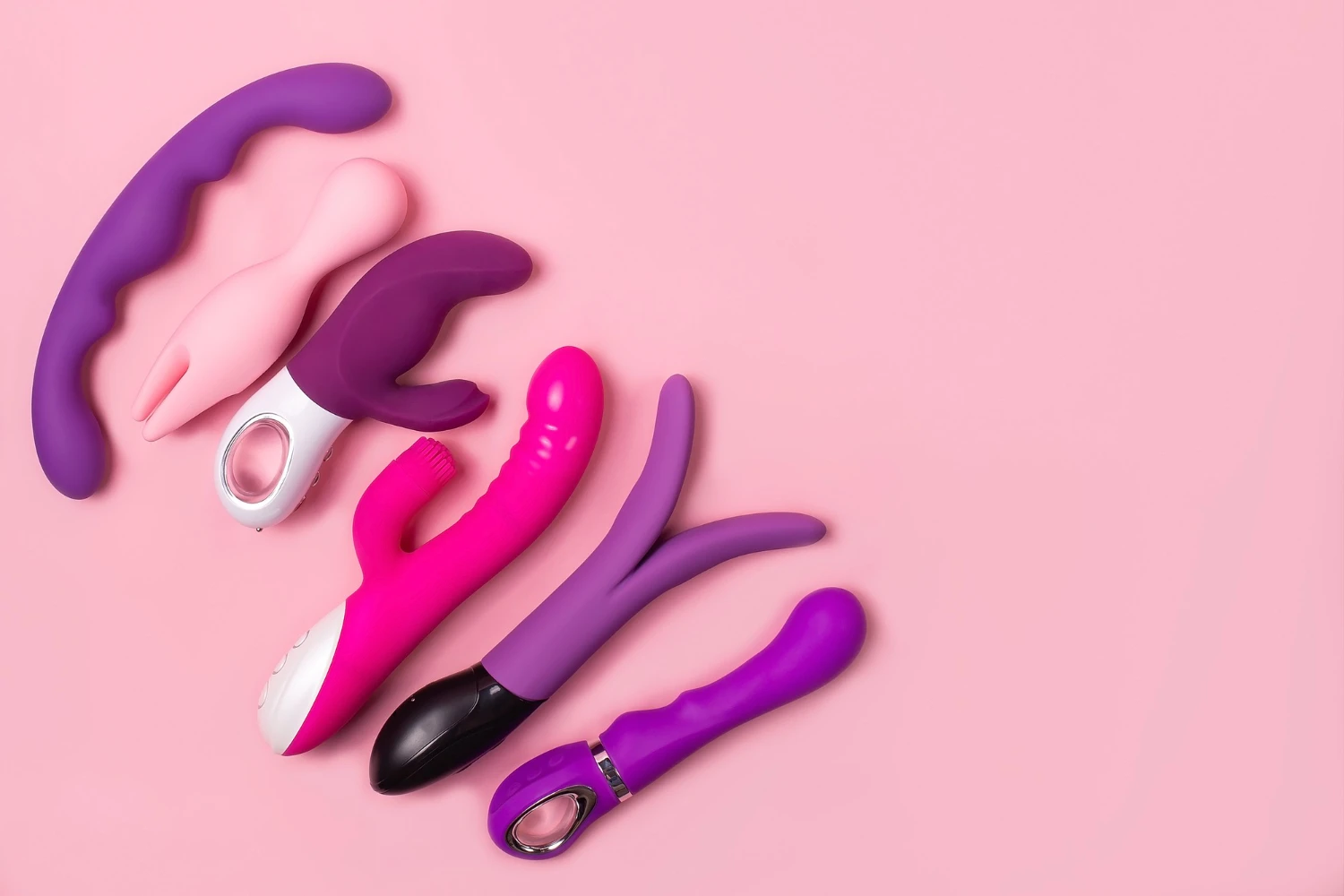 на розовом фоне изображены двойные вибраторы разных моделей и цветов