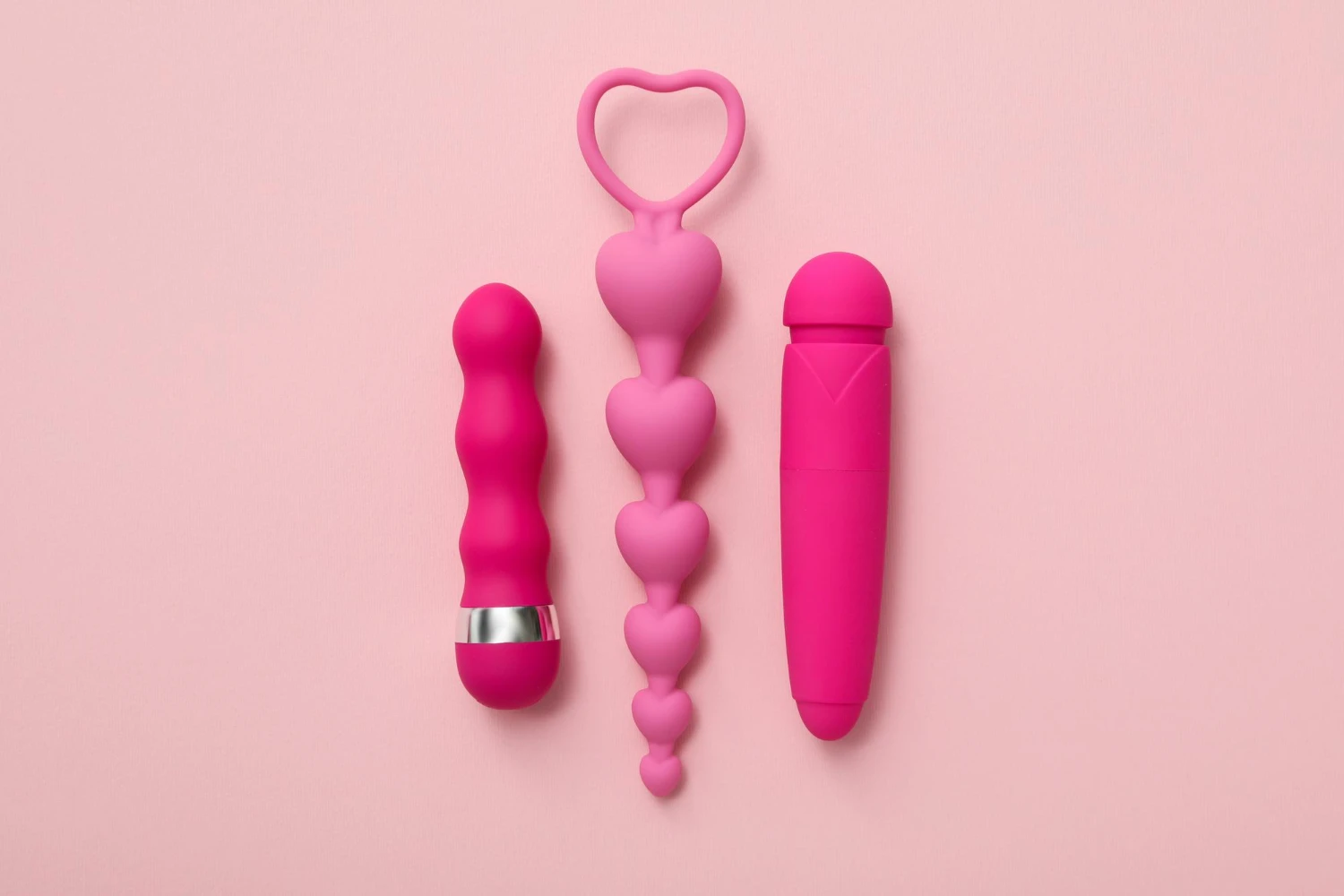 на рожевому фоні зображені рожеві вібратори та рожеві анальні буси