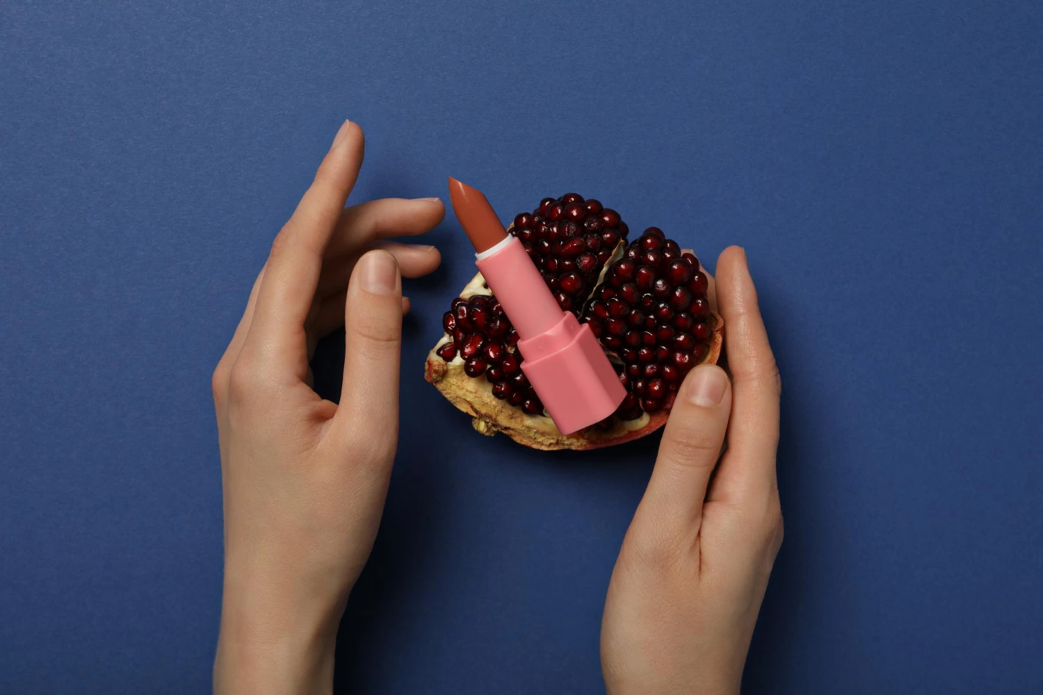 на фото изображен вибратор в виде помады и гранат на фиолетовом фоне