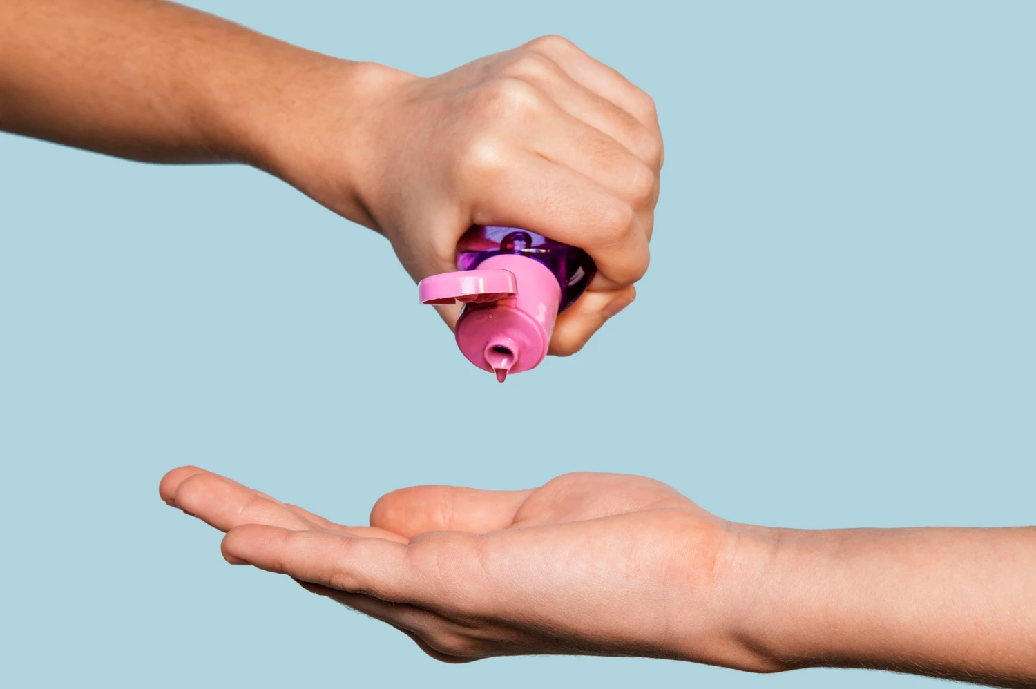 на фото зображений водний лубрікант в руках на блакитному фоні