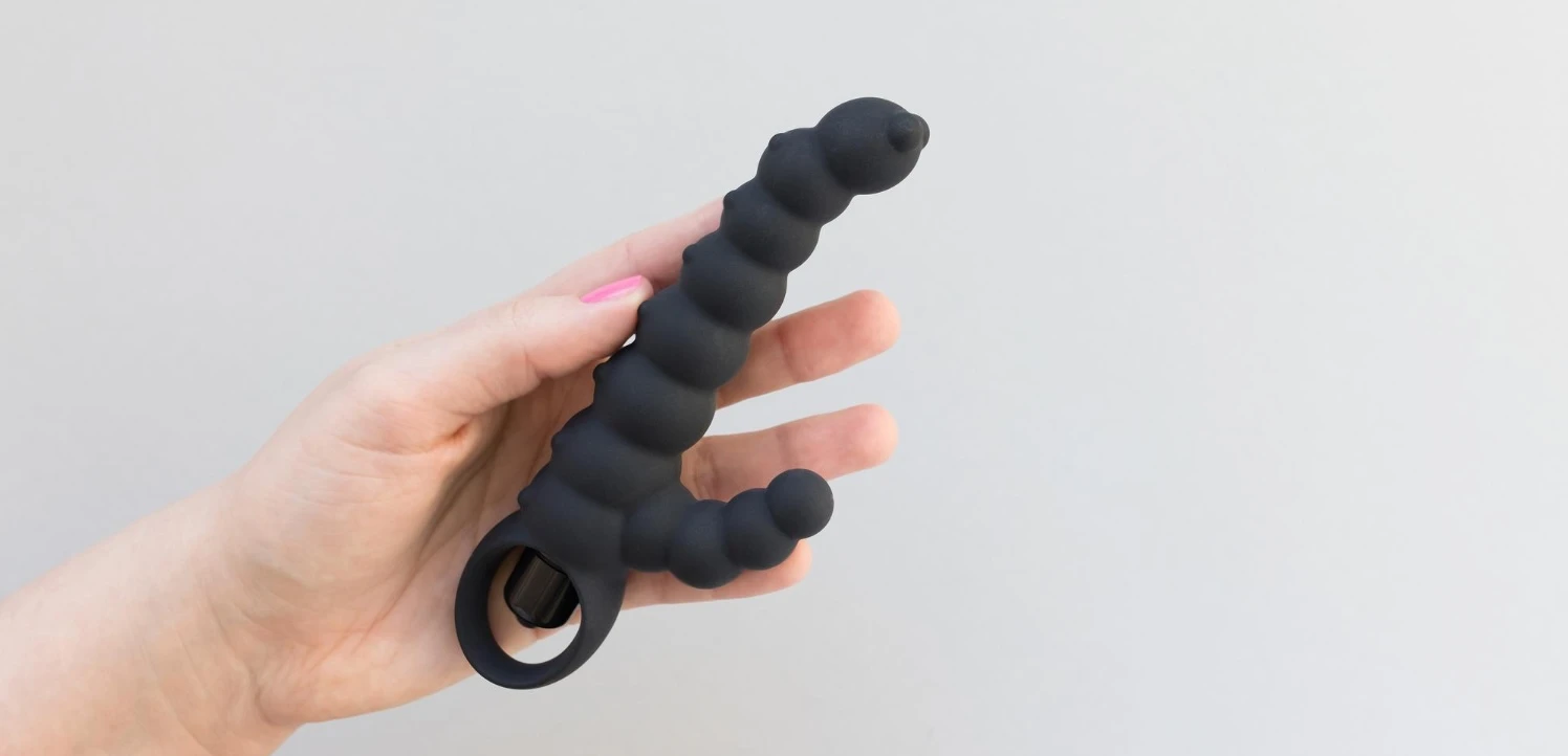 на сірому фоні зображена чорна силіконова анальна іграшка з вібрацією