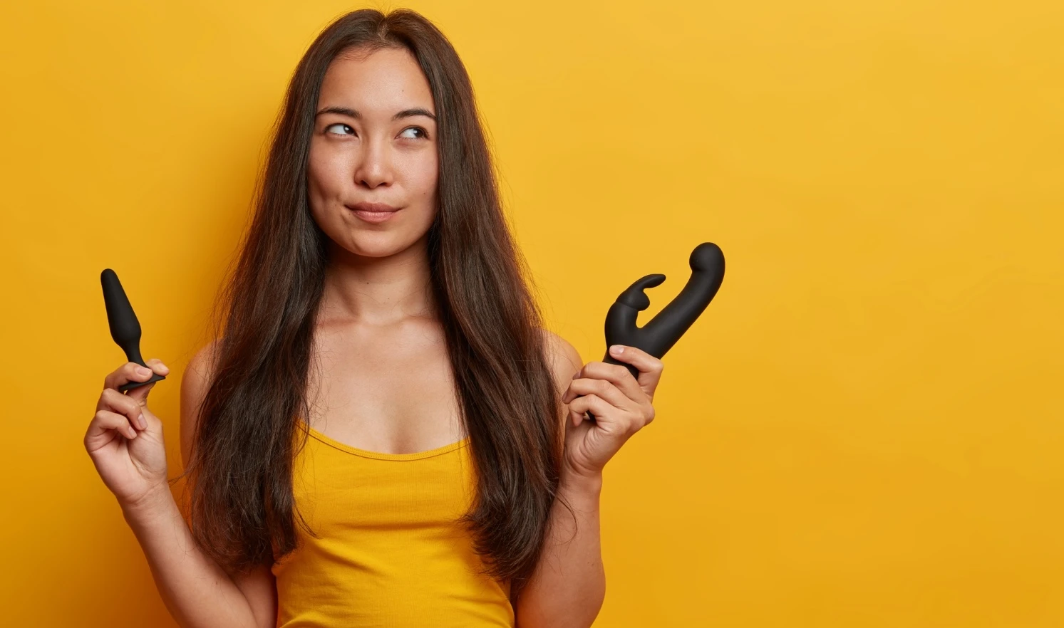 на желтом фоне изображена девушка с анальными пробками в руках