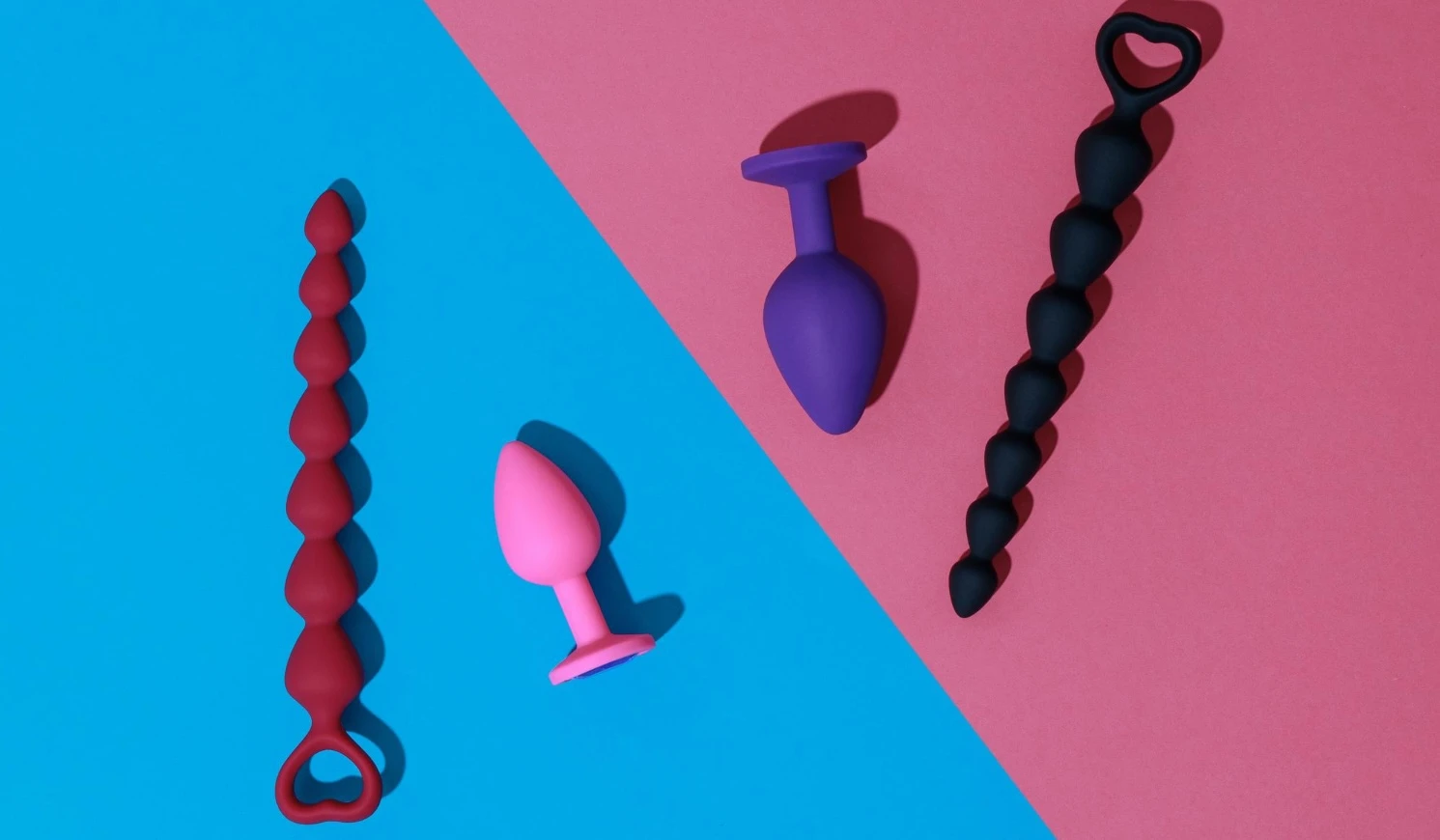 на цветном фоне изображены силиконовые анальные игрушки: анальная пробка и анальные бусы 