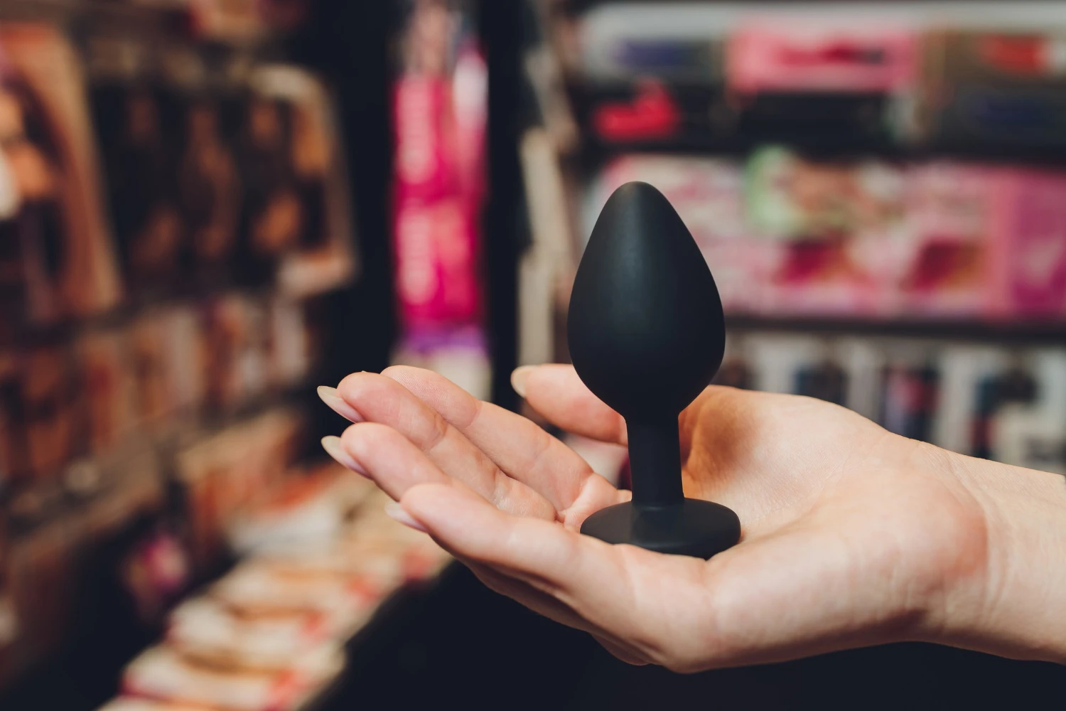 на фото зображена анальна втулка чорна силіконова в руці жіночій