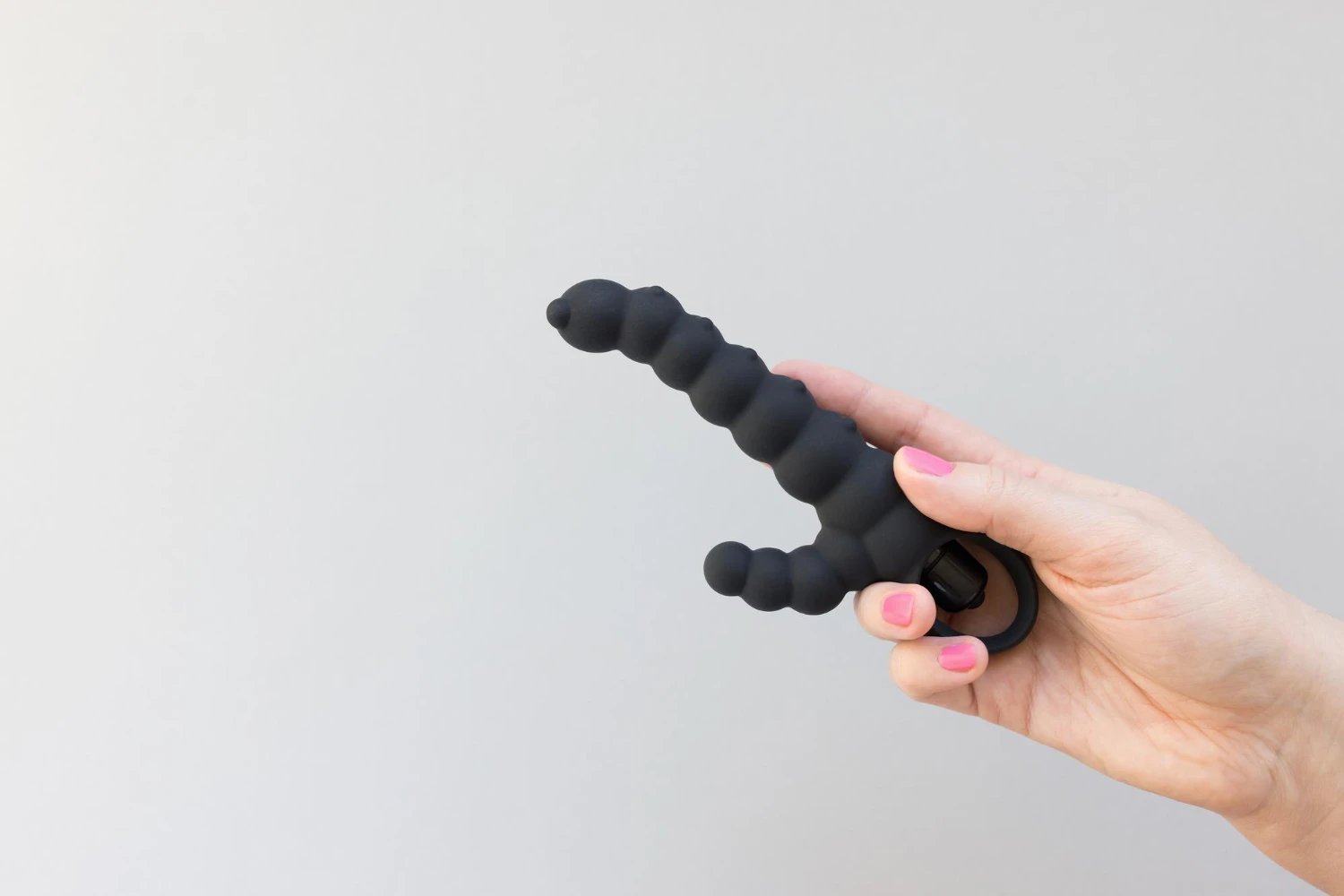 на сером фоне рука с черным мужским вибратором анальным