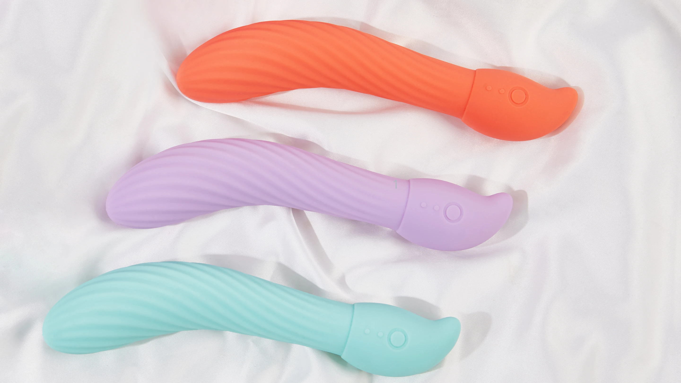 на фото зображені три реалістичні вібратори пастельних кольорів