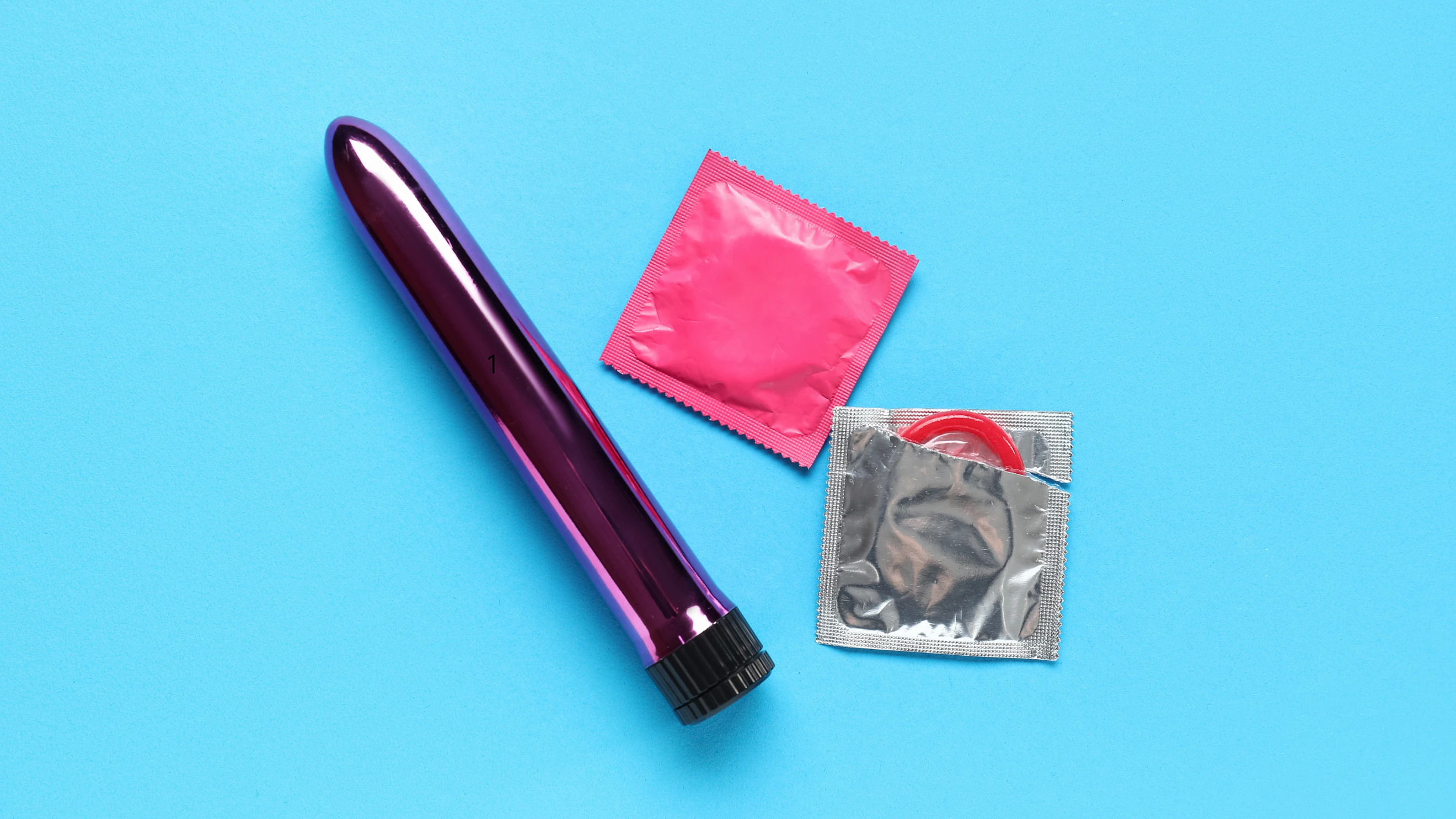 на голубому фоні зображений металевий ділдо з презервативами