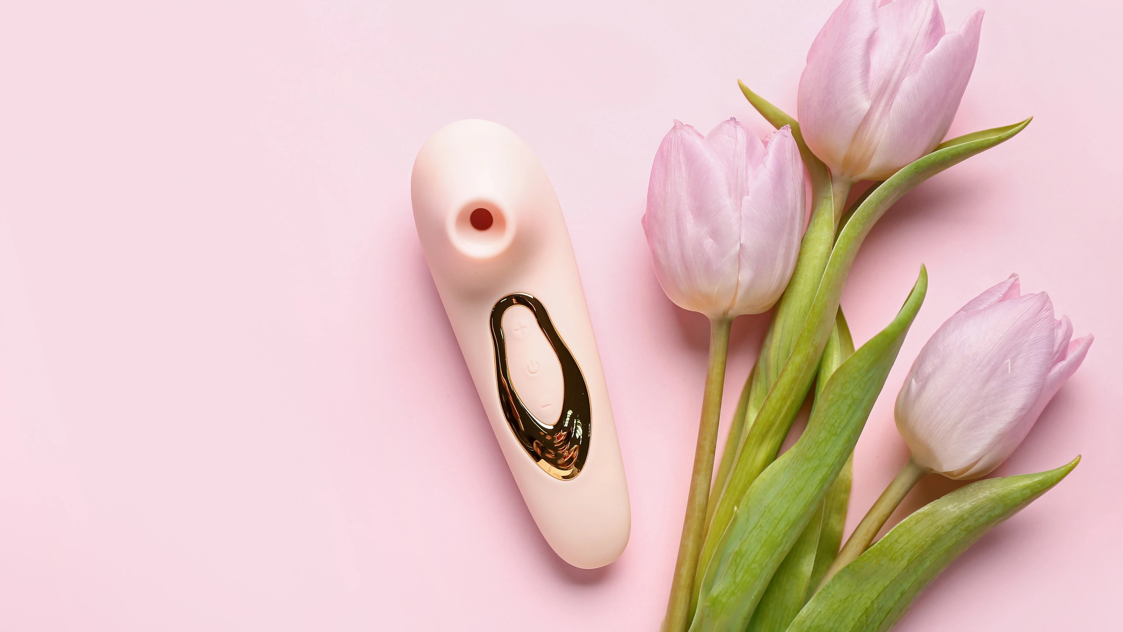 на рожевому фоні зображений кліторальний стимулятор та три рожевих тульпани