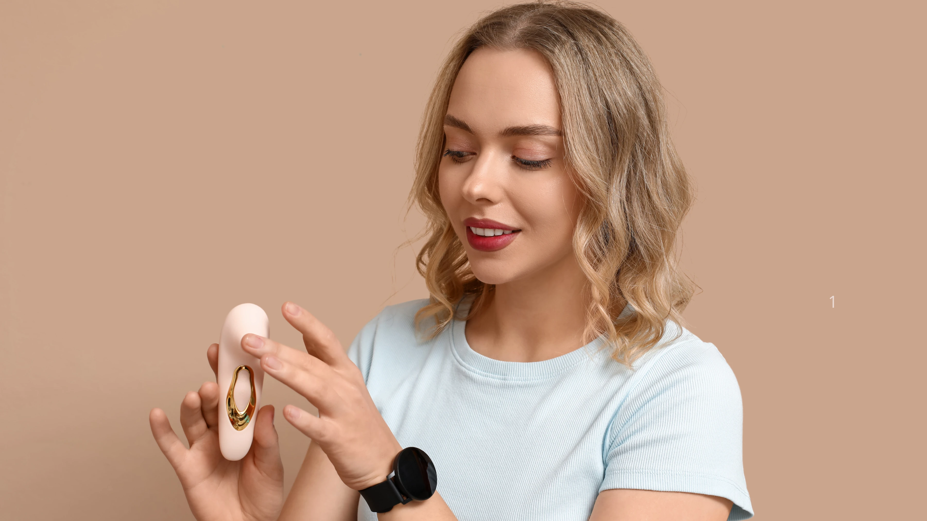 зображена дівчина, яка держе в руках кліторальний вібратор стимулятор та посміхається