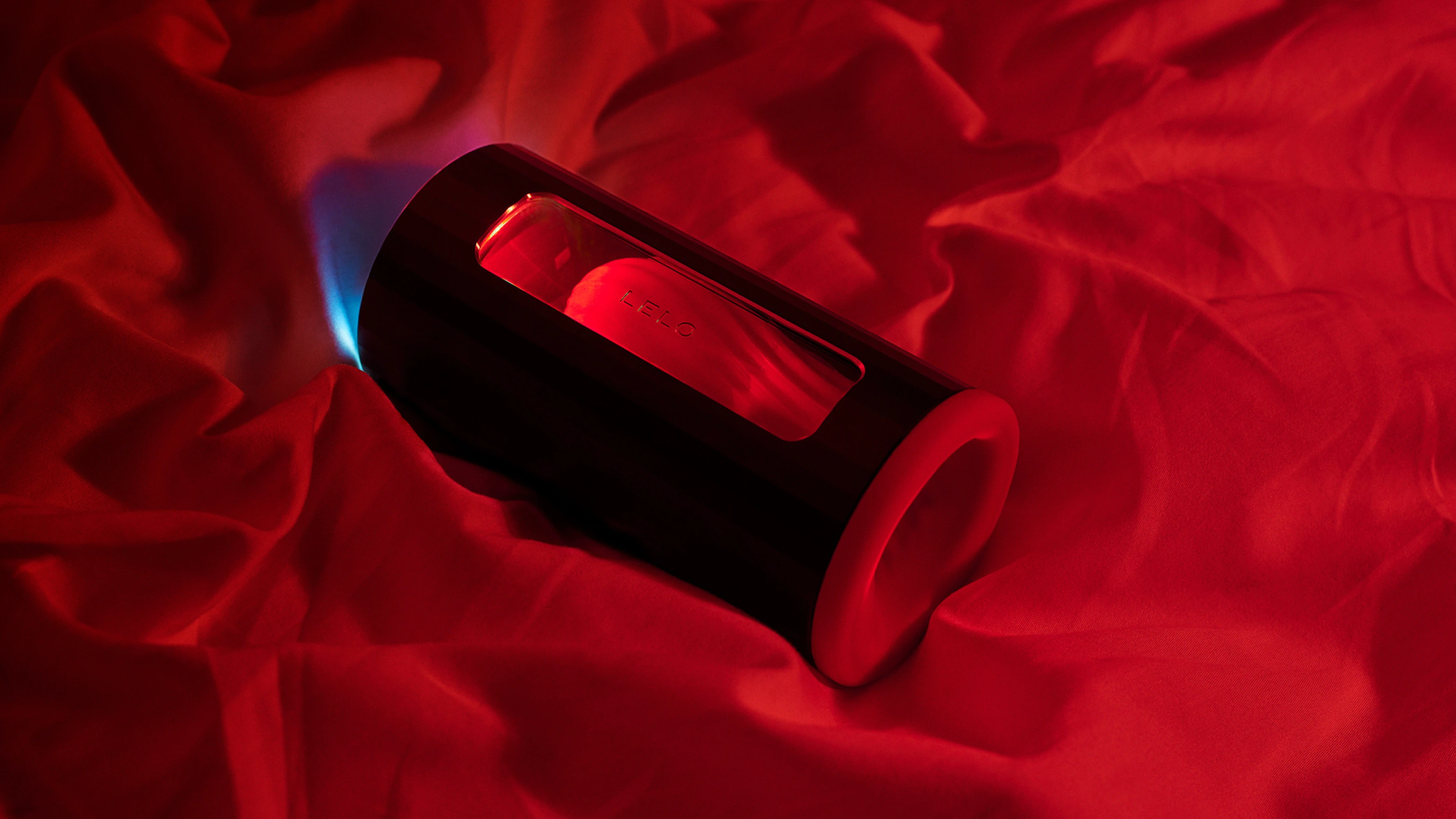 на фото изображен автоматический мастурбатор бренда Lelo на красной шелковой простыни