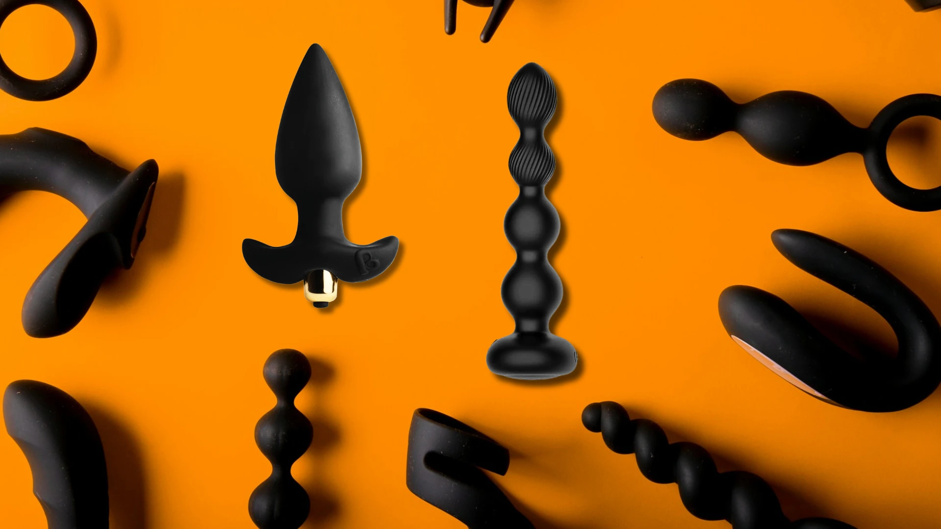 на оранжевом фоне изображены разные виды анальных вибропробок черного цвета