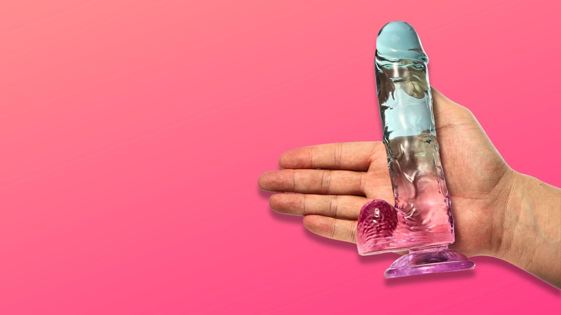 на розовом фоне изображен прозрачный розовый фаллоимитатор на присоске с руке