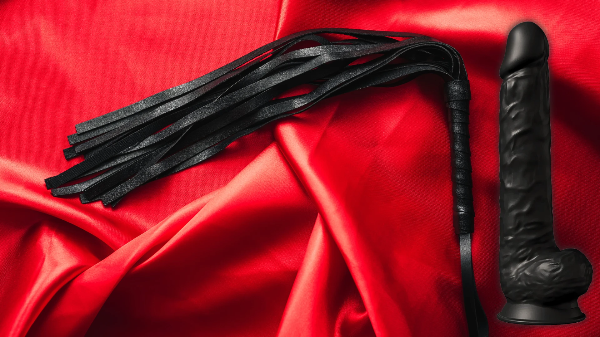 на червоному шовковому простирадлі зображений чорний гумовий член на присосці та пльотка БДСМ