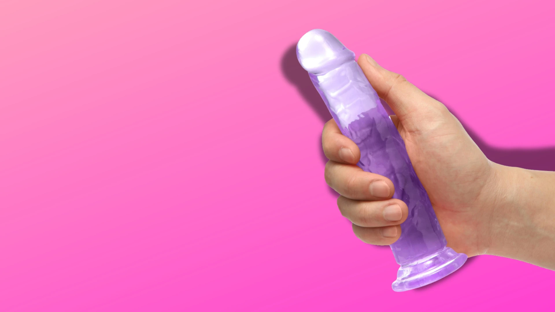 на рожевому фоні зображений прозорий гумовий фаллос на присосці на рожевому фоні