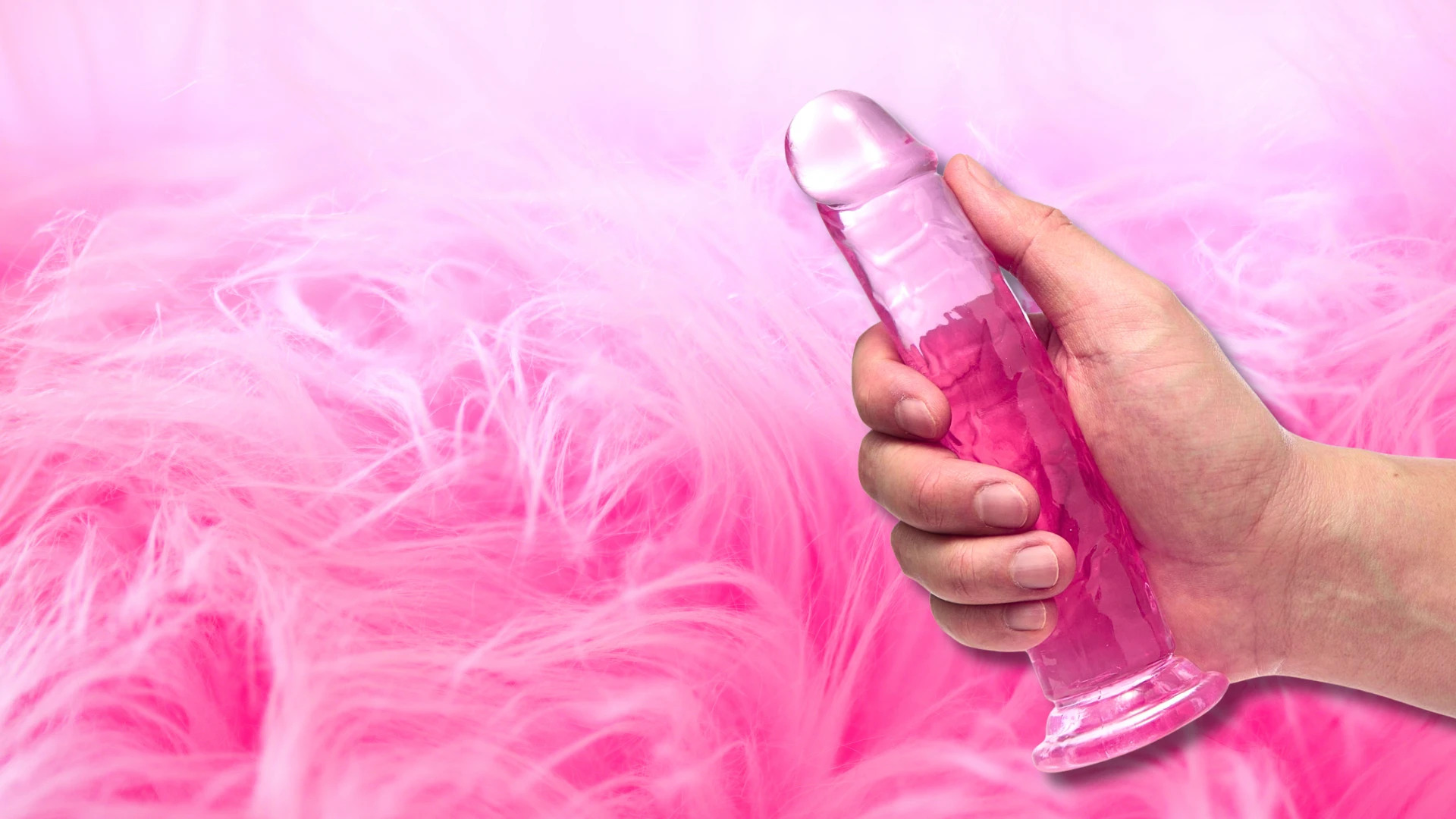 на фото зображений рожевий ділдо в руці на красивому рожевому фоні