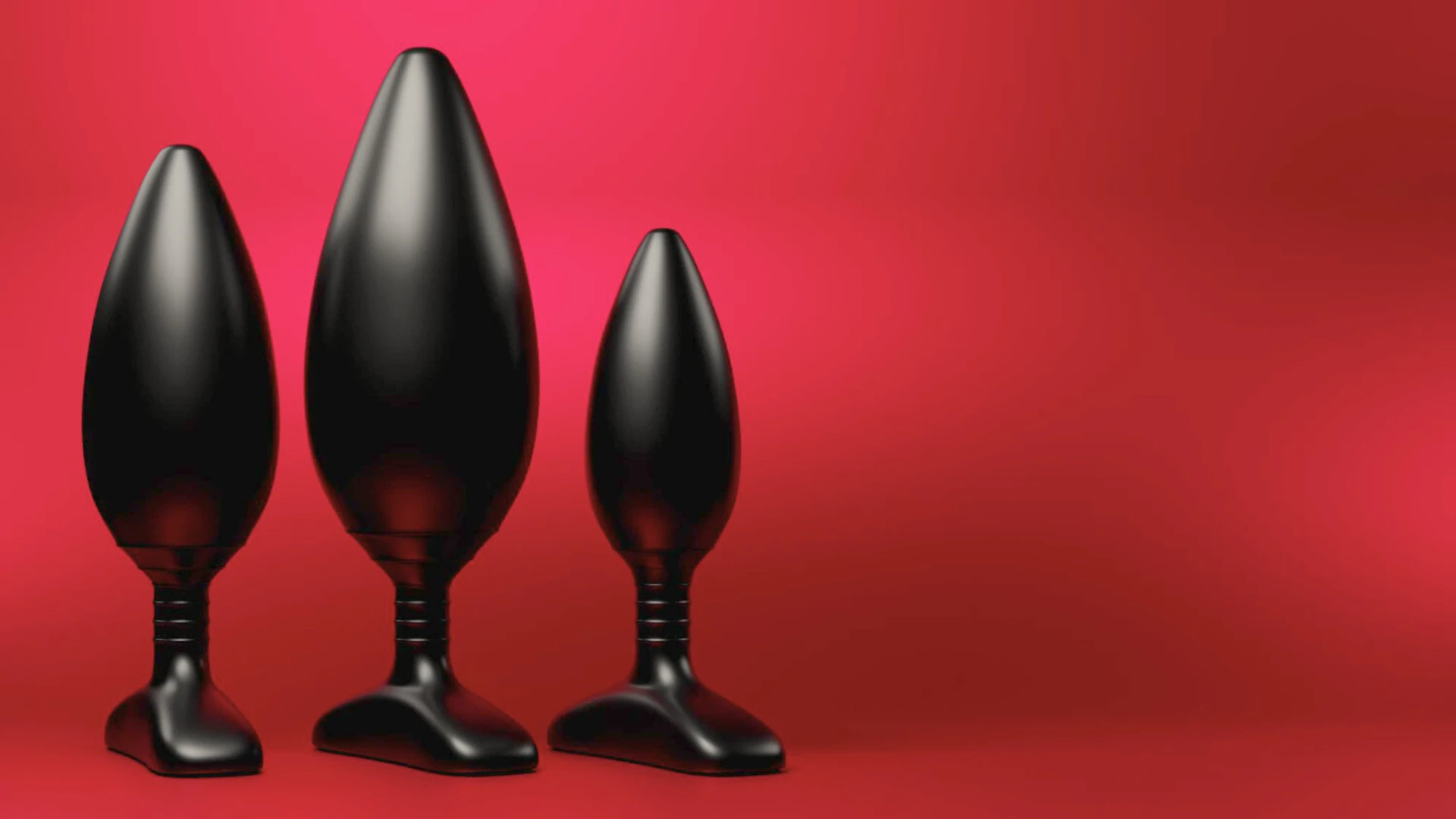 на червоному фоні зображен набір з трьох чорних залізних анальних втулок різного розміру