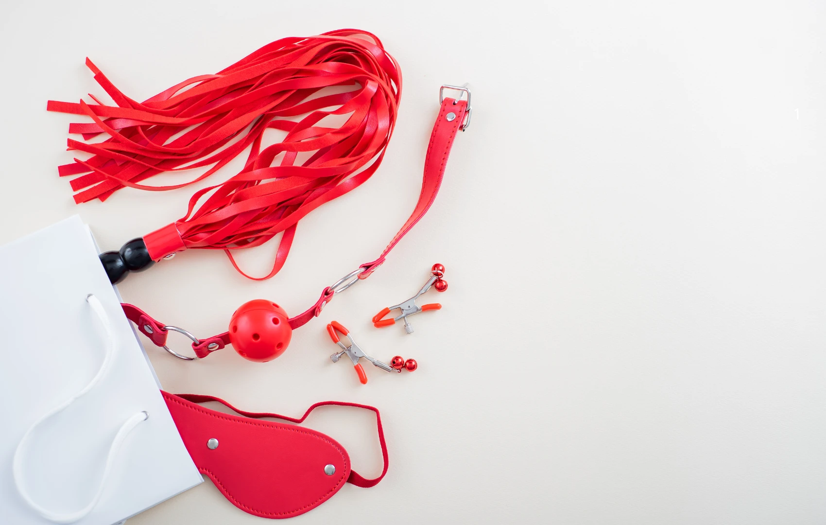 на белом фоне изображена красная плетка для ролевых игр и другие бдсм игрушки красного цвета