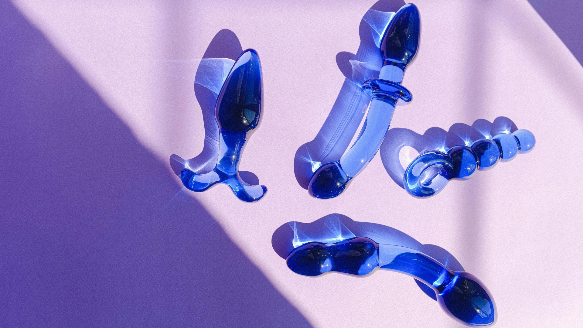 на розовом фоне изображены синие стеклянные дилдо разных моделей